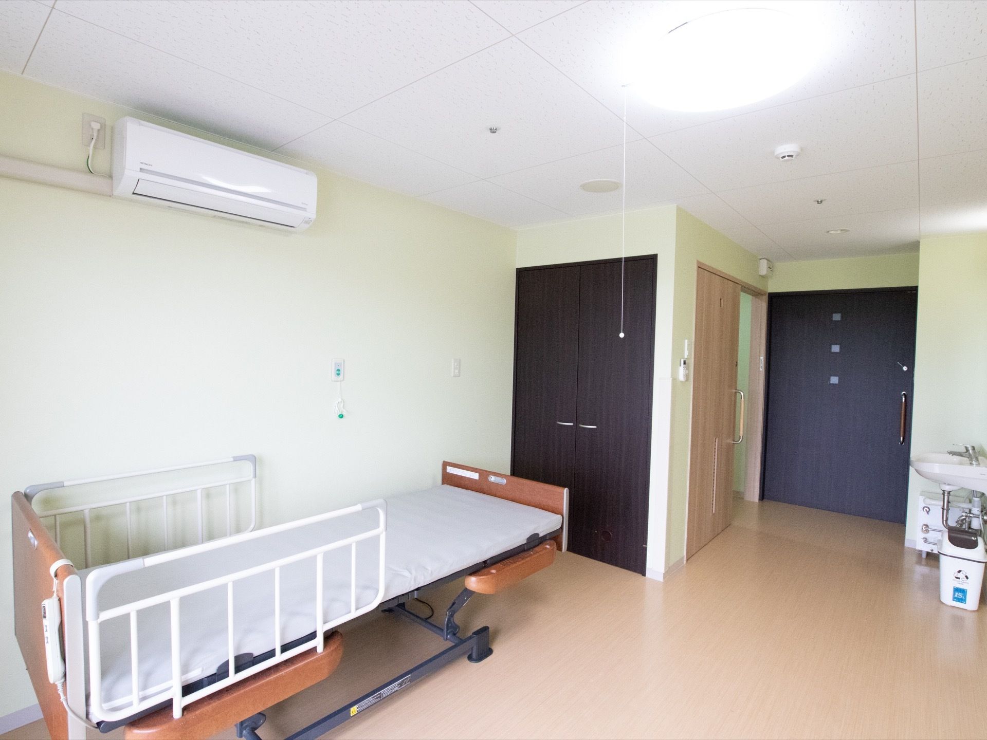 居室内にはベッドがあり、両脇に転落防止用の柵が取りつけられている。ベッド横の壁には施設スタッフを呼び出すためのボタンが配備されている。