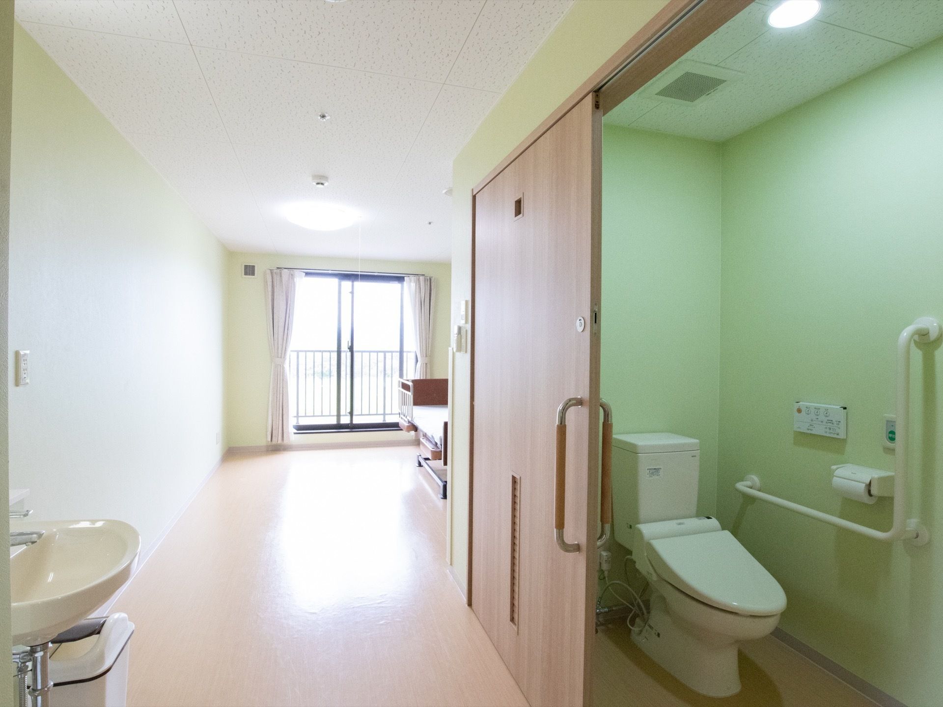 トイレスペースを木目調のスライド式扉で確保している居室