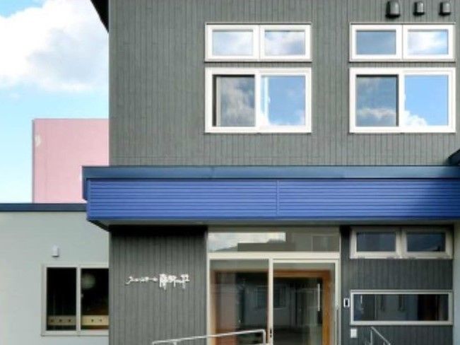 2階建ての建物はグレー系で日当たりもよく、外壁にはホームの名前が書かれている。