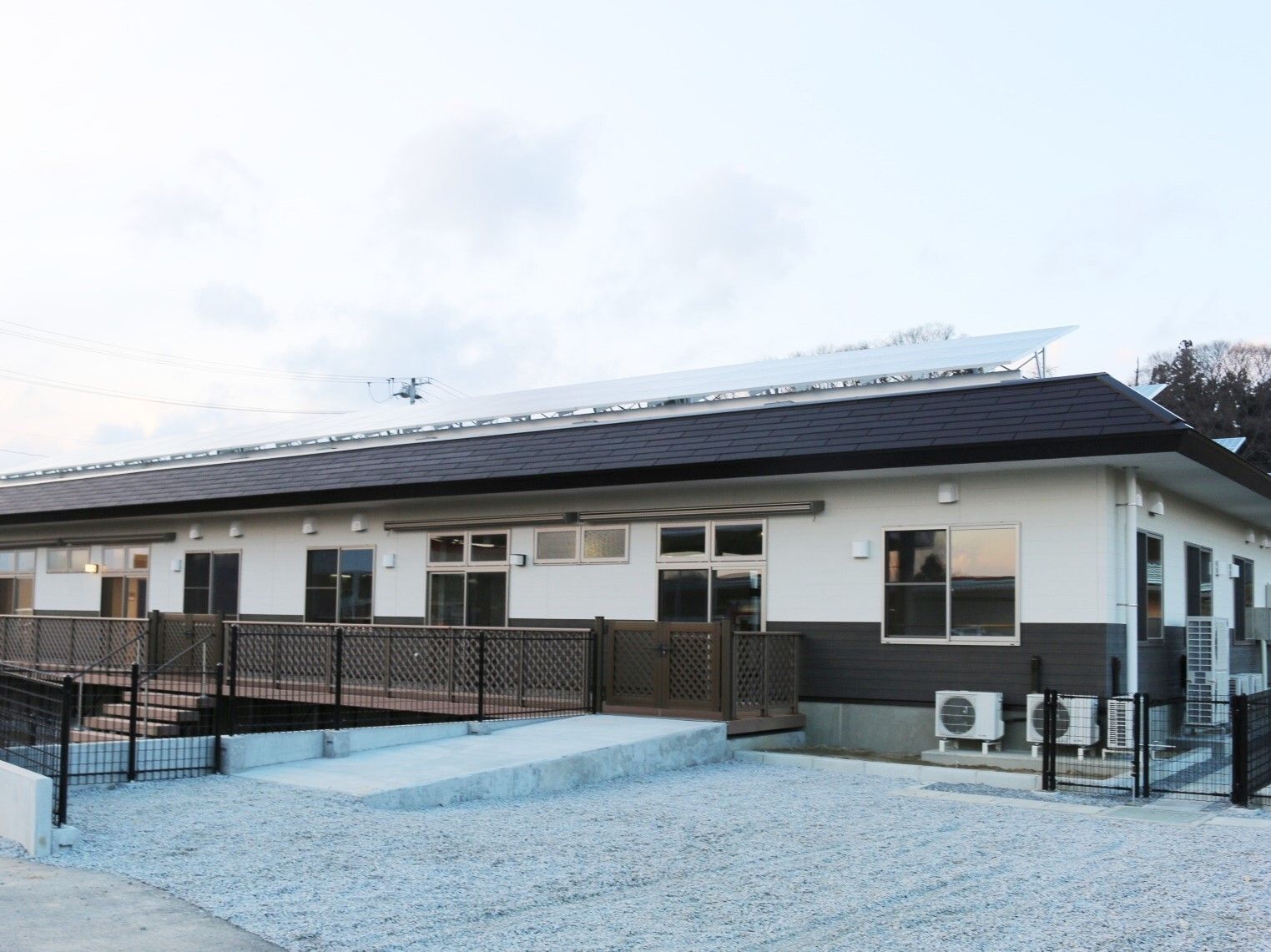 ブラウンと白の平屋建ての建物。ホーム周辺には緑がある。