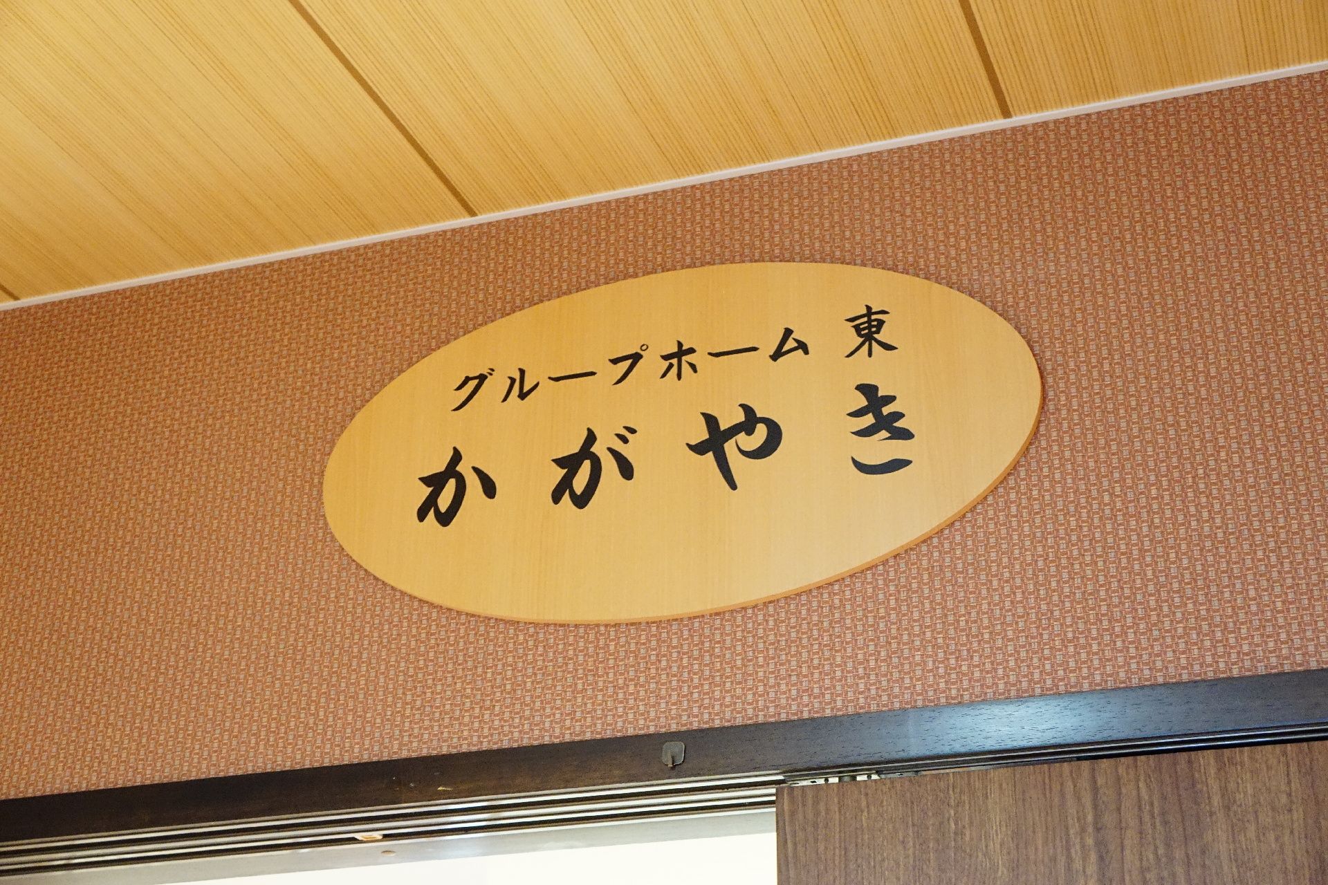 玄関ドアの上に設置され、施設の名前が書かれている木の看板