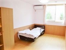 居室にはエアコンが設置され、カーテンが付けられた窓があり、ベッドなどが並んでいる。