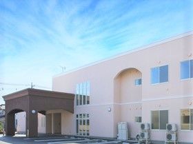 ２階建てのベージュの建物。玄関には車寄せも付けられている。