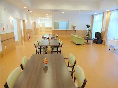 大きな窓があり明るい。ダイニングテーブルが複数置かれ、肘置き付きの椅子がセットされている。