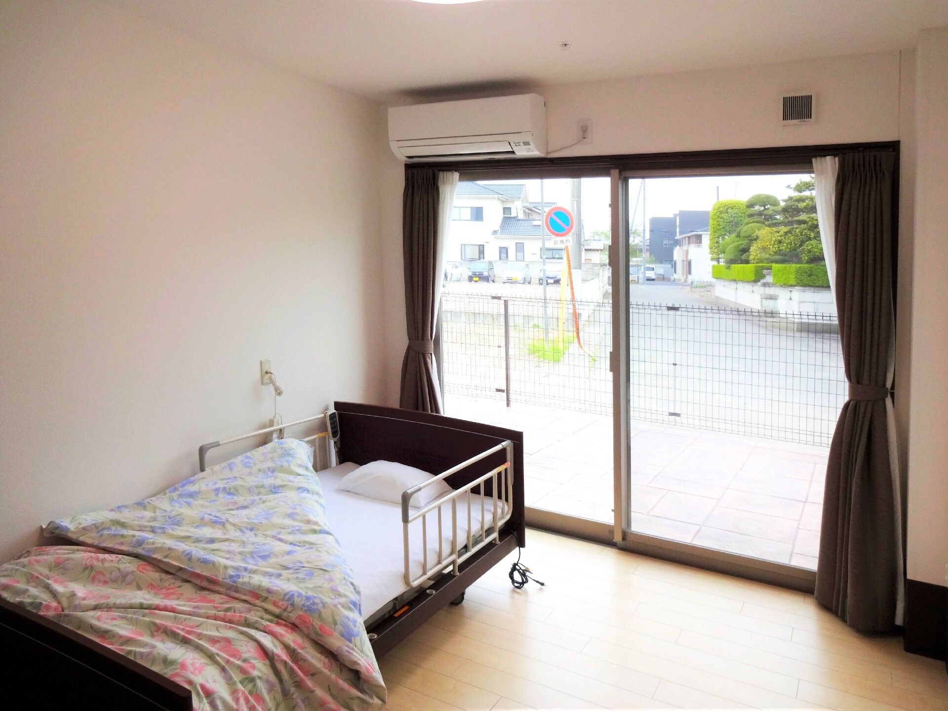 平屋建ての建物で玄関には屋根が付き、玄関にはホーム名が書かれ、紫の看板も立っている。