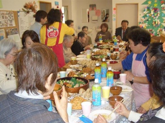 季節行事で豪華なお寿司を楽しんでいる様子。高齢者とスタッフが一緒に楽しんでいる