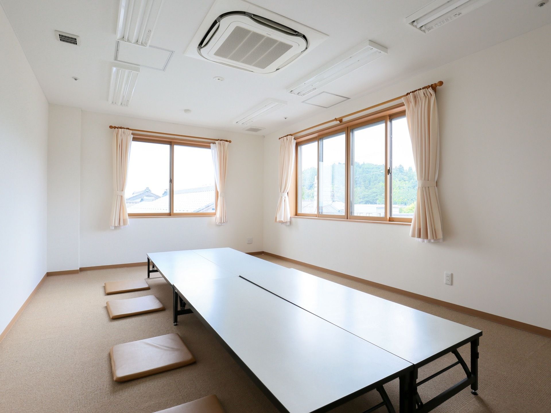 絨毯が敷かれた広い部屋に低い折り畳みテーブルが４つ設置されている。テーブルの周囲には座布団が置いてある。