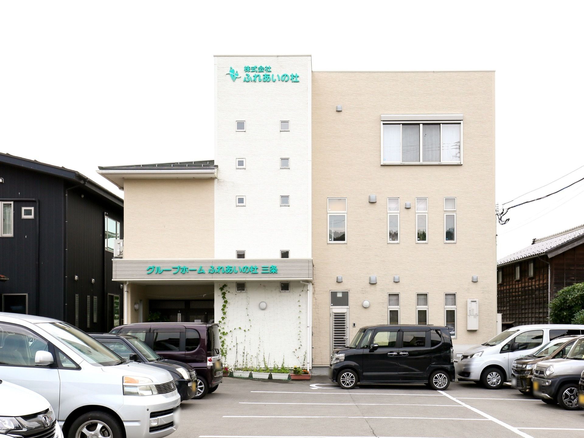 施設は３階建ての大きな建物で、１階の屋根部分には緑色の文字で施設名が表示されている。施設前には駐車場がある。