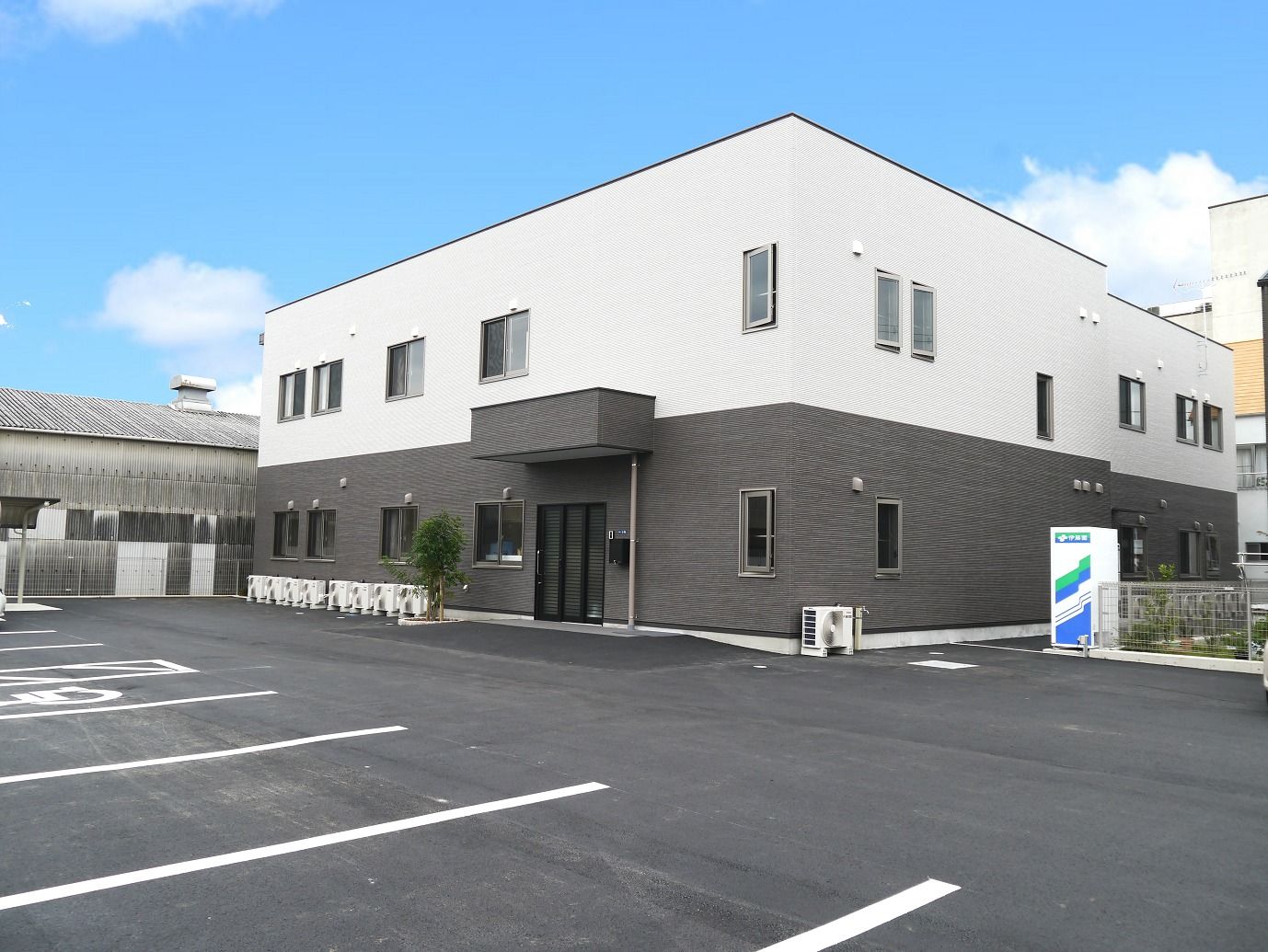 2階建ての建物のある敷地内には駐車場があり、建物の周りには自動販売機などもある。