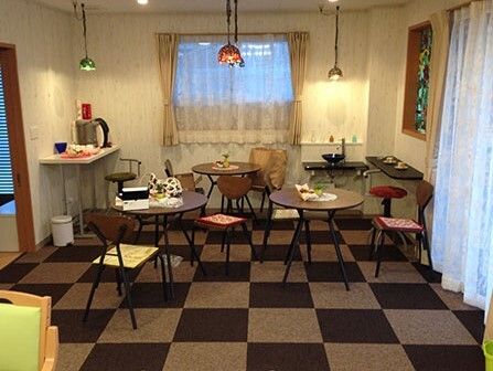 市松模様のじゅうたんが敷かれている施設のリラックススペース。テーブルと椅子のセットが置かれている様子