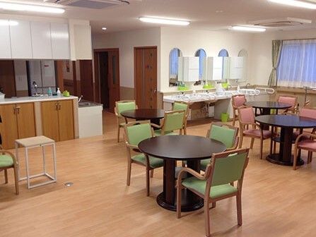 丸テーブルと椅子のセットが複数置かれている施設内の食堂スペースの様子