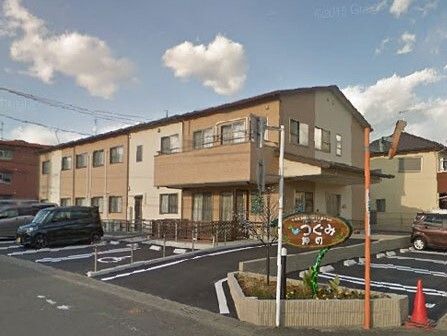 優しい色合いの建物の外観写真。駐車場スペースが確保されている敷地内