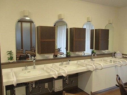 手すりがついた洗面台が並んでいる様子。施設の共有スペースにある安全な設備の写真