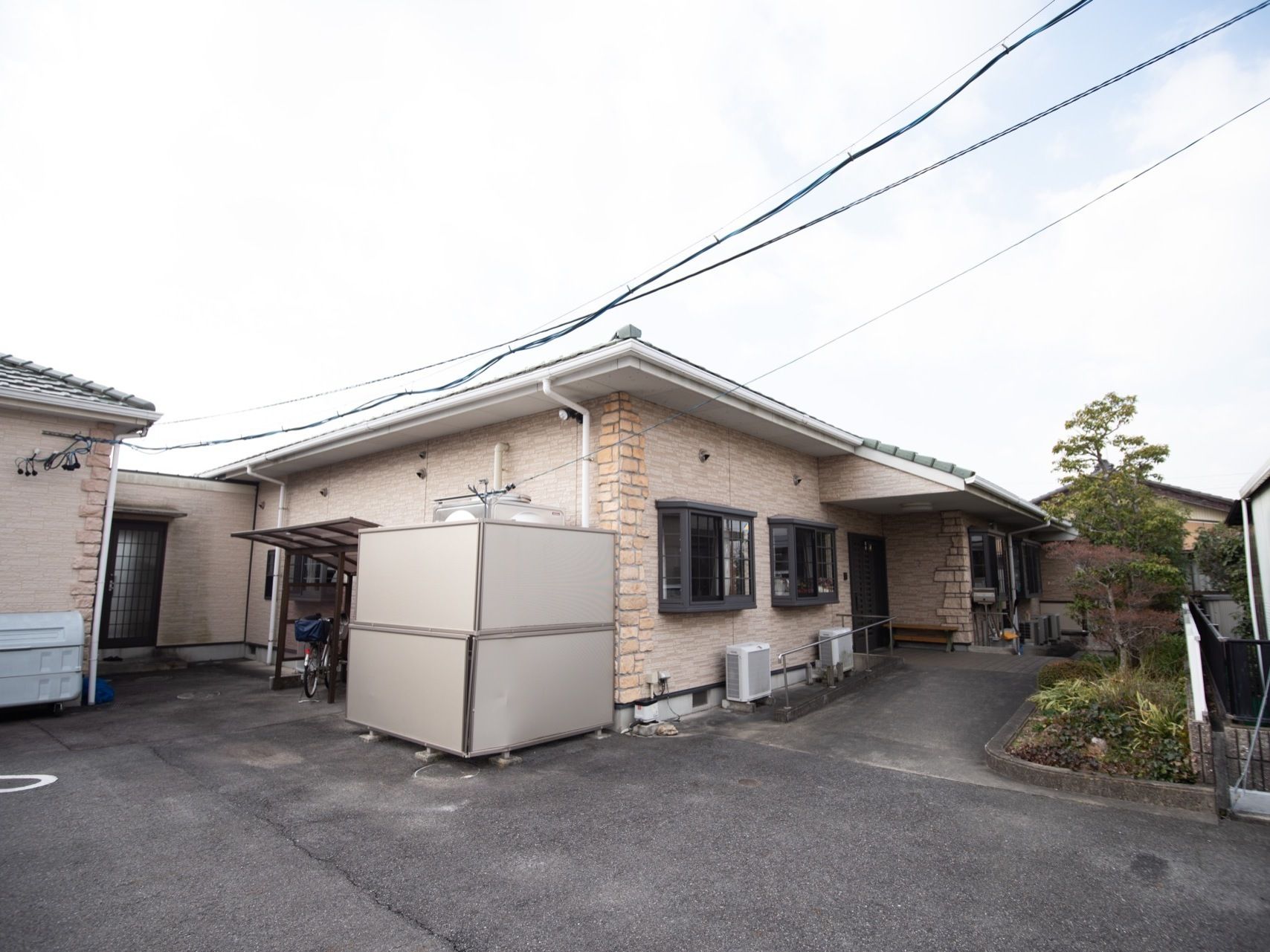 平屋建ての施設である。出窓やスロープが完備され、横には植栽が施されている。テラス屋根付きの駐輪場が設けられている。