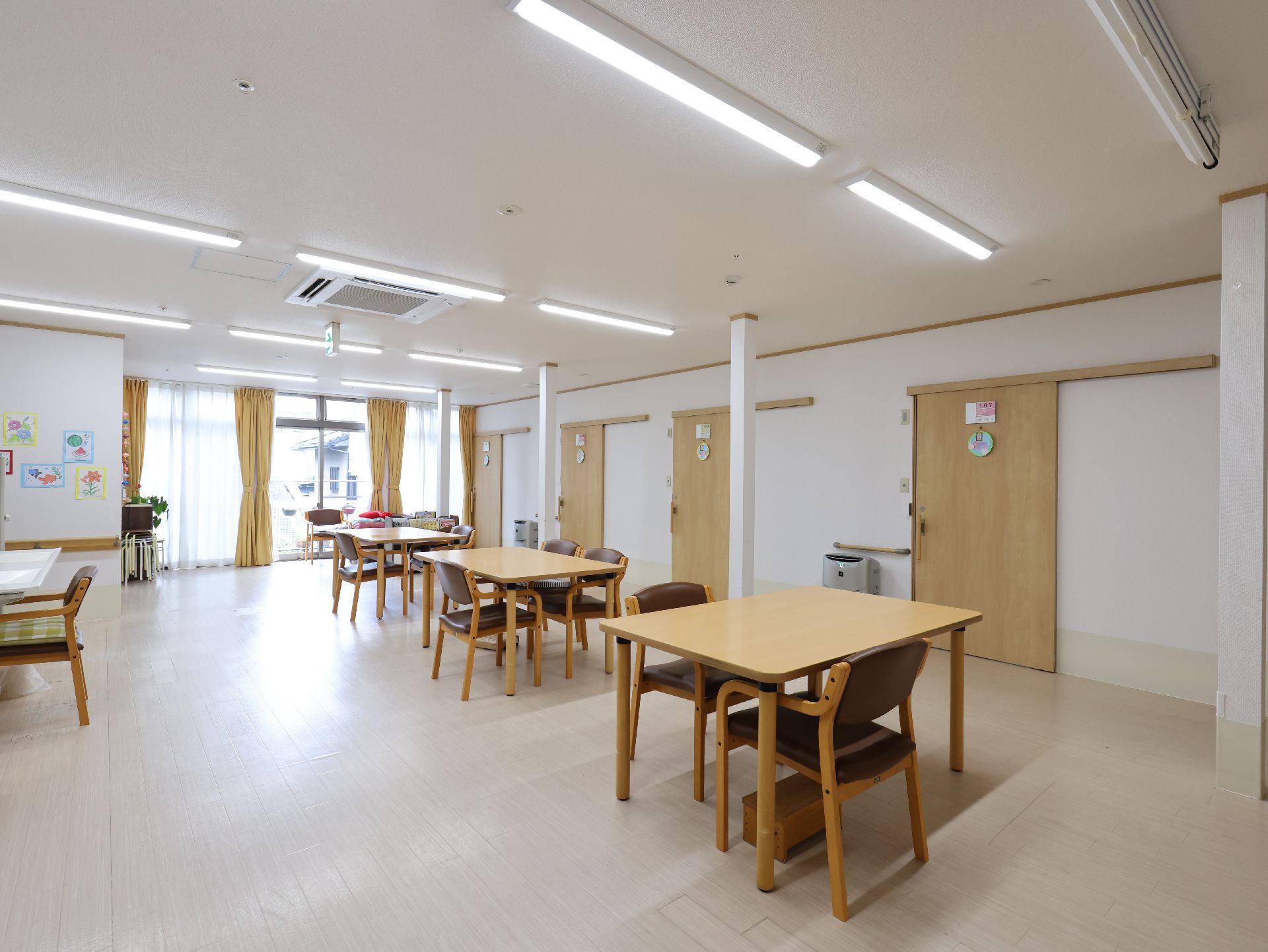 木製の机が並んでいる白い壁の広間