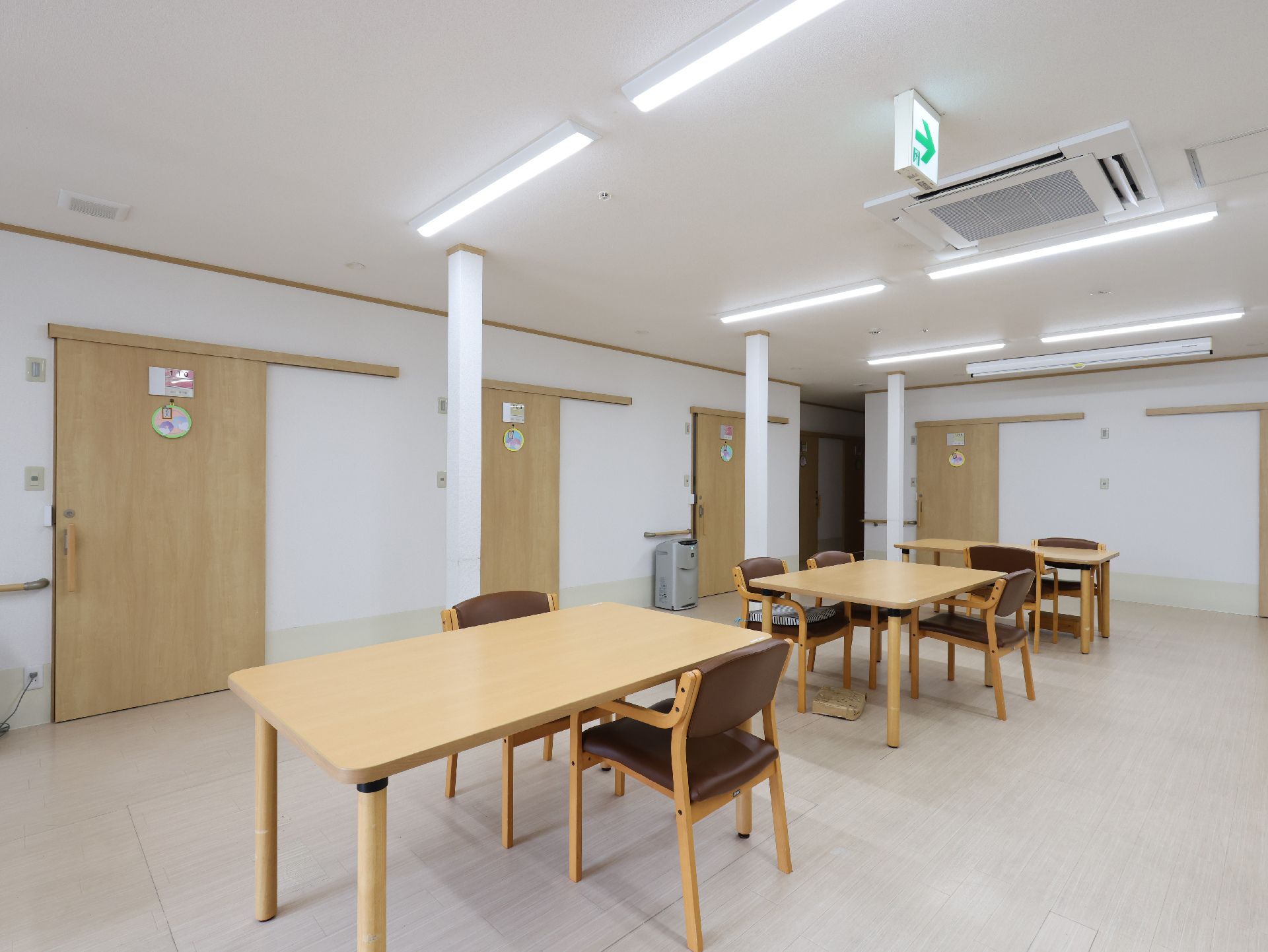 木製の机が並んだ白い壁の広間