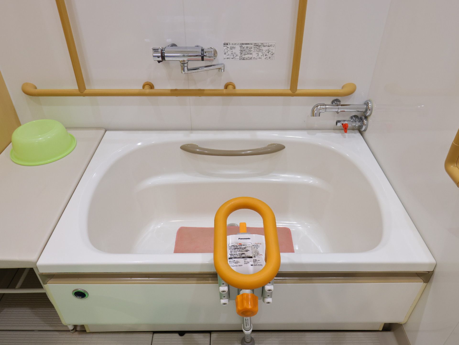 手すりが付いた白い壁の部屋にある浴槽