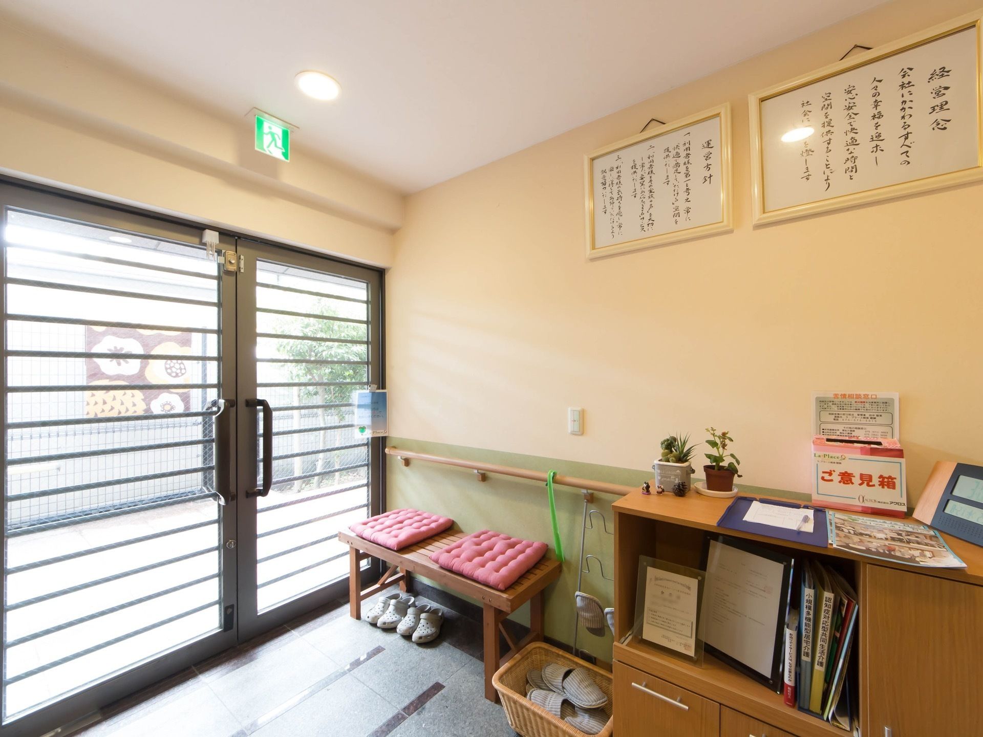 大きなガラス扉の玄関である。たたきは石が貼られており、壁際に椅子がある。壁に経営理念や運営方針が掲げられている。