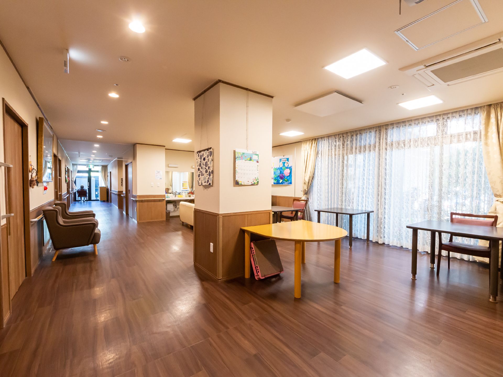 エプロンを付けた若い男性スタッフに付き添われて屋外で過ごす時間を楽しんでいる車いすの高齢女性。