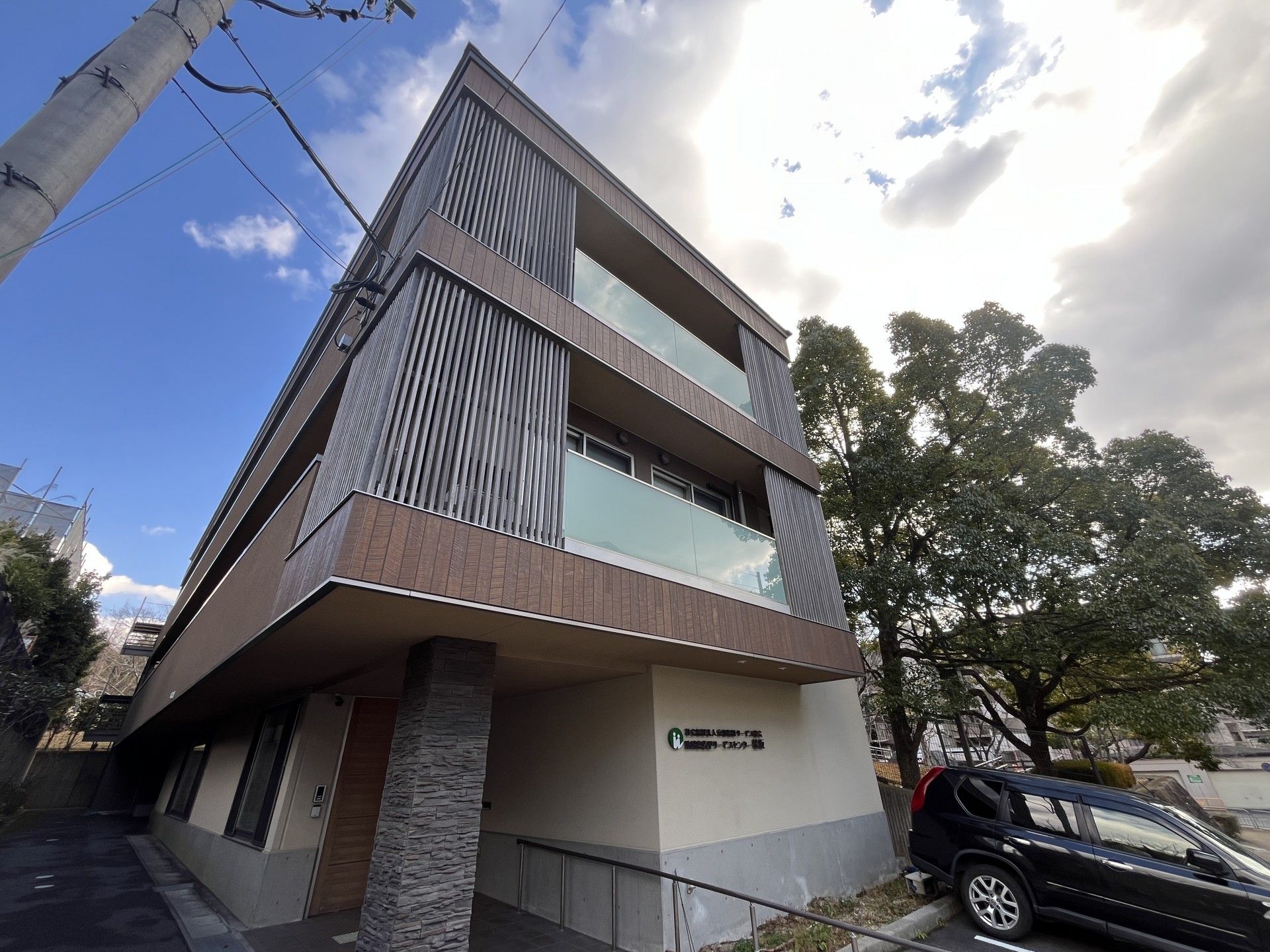 なにかを見て笑顔で手をたたいている高齢女性とスタッフの様子。施設での一場面の写真