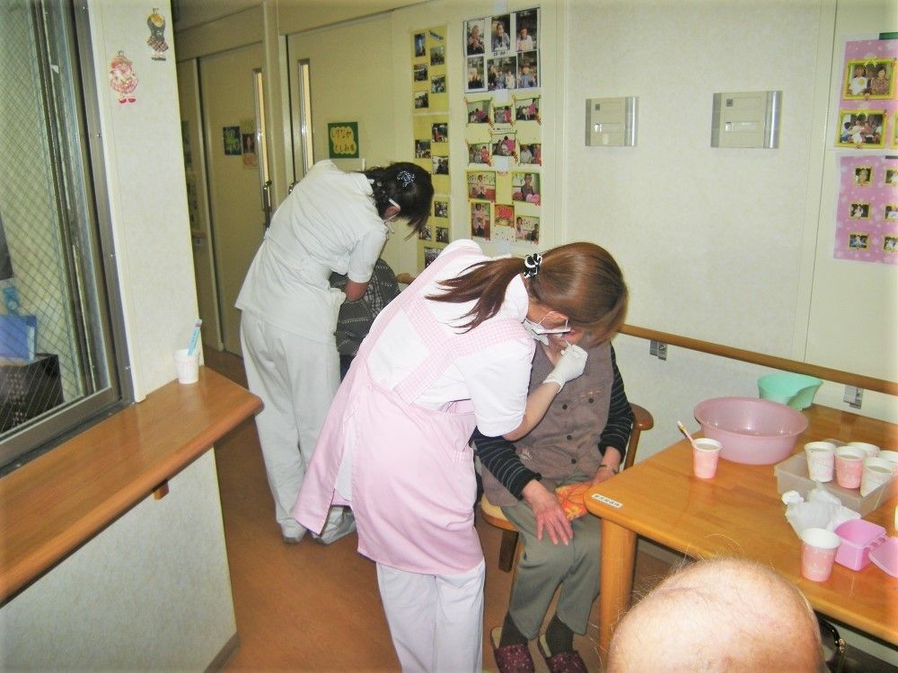 高齢者の口腔ケアをしている歯科医とそのスタッフ。施設内で行われているケア