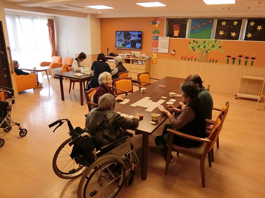 壁には入居者の作品らしきものが飾られ、ダイニングテーブルが二組置かれ、それぞれのテーブルでレクリエーションをしている。