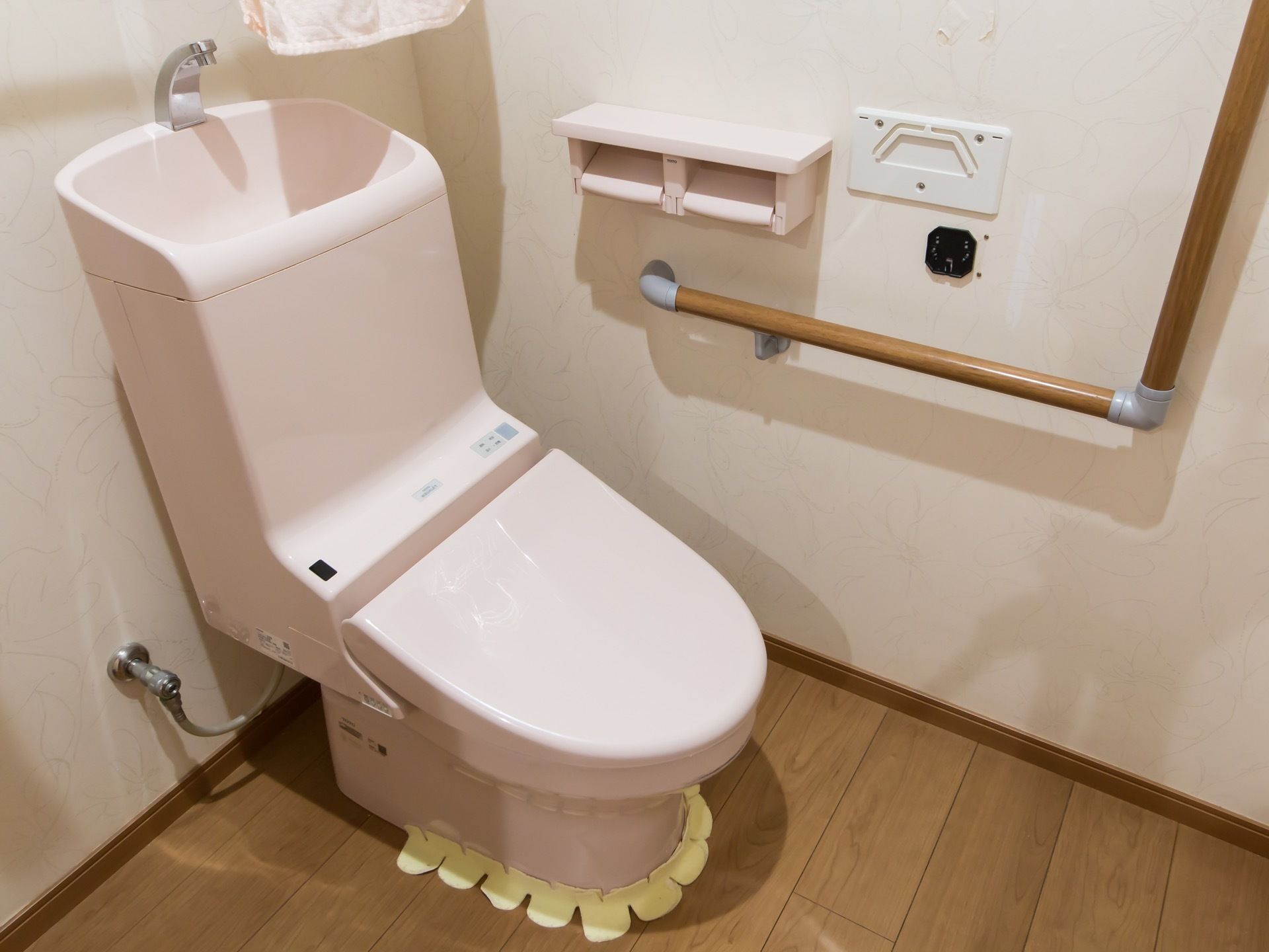 洋式の便器があり、便器の上は手洗い場になっている。周囲の壁には手すりなどが取り付けられているのが見える。