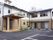 ベージュとアイボリーの２階建ての建物は日当たり良好で玄関先には手すり付きのスロープがあり、駐車場もある。