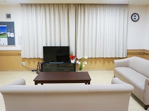 カーテンが付いた大きな窓が付いているリビングにはテレビやソファ、カレンダーなどがある。