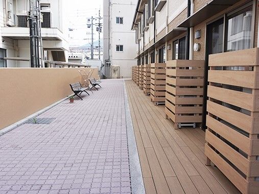 ベンチが２台置かれたテラスは広く、余計なものは置かれていない。周りには背の高い建物がある。