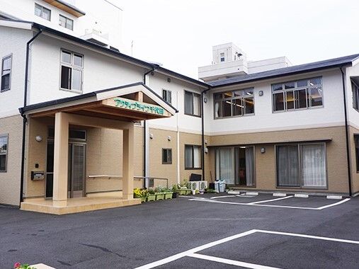 エル字型の２階建ての建物は日当たり良好で敷地内には駐車場もある。玄関先には手すり付きのスロープも付いている。