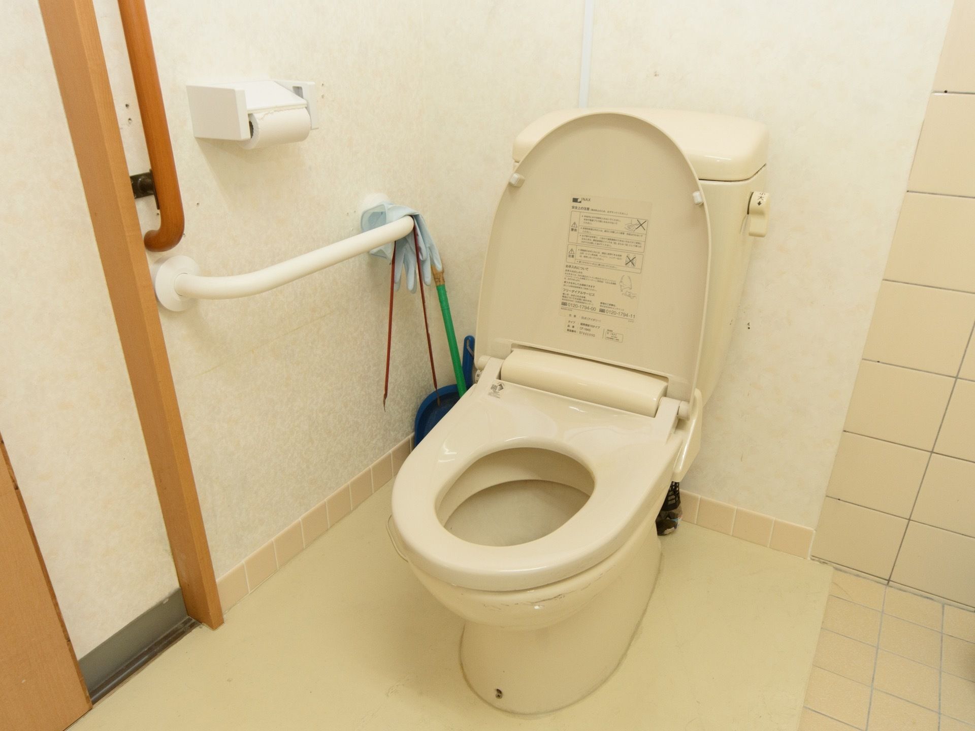 トイレ内の便器のそばには手すりがあり、しっかり体を支えてお使いいただける。タイル貼りの壁で、清潔に保たれている。