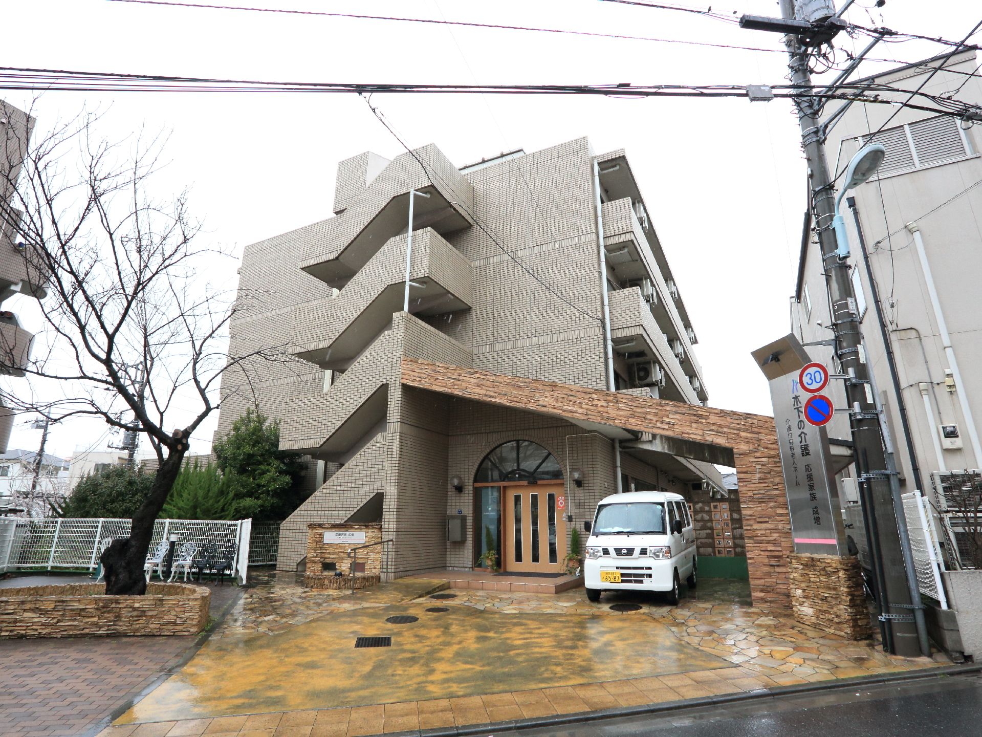 施設はデザイナーズマンションのような外観。玄関前は広くスロープがある。施設前に大きな木が植えてあるのが特徴。