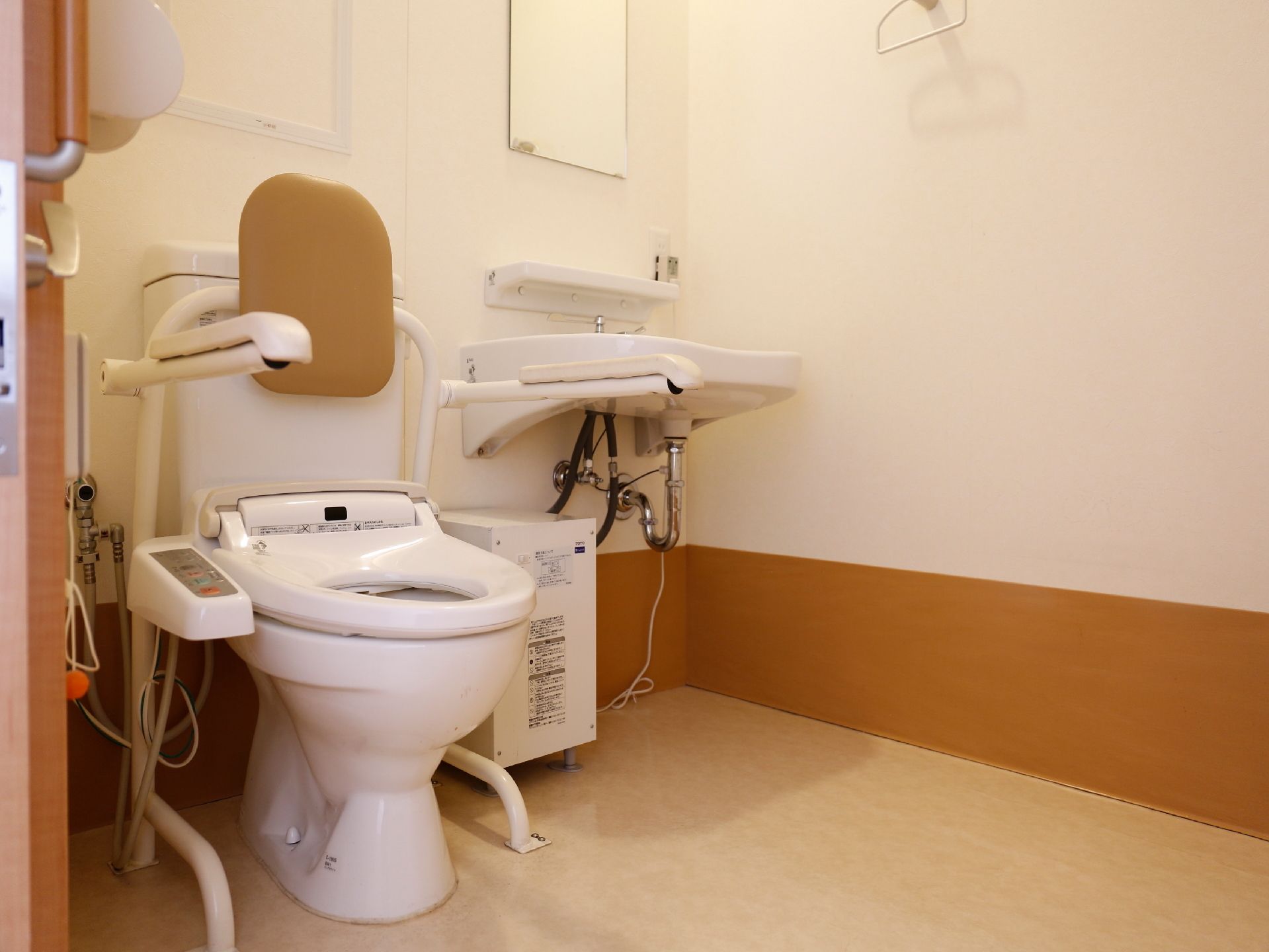 広めのスペースが確保された室内には、隣り同士にトイレと洗面台が設置されている。トイレには両側に手すりが取りつけられている。