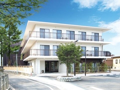 白い壁で明るい印象で、3階建ての施設入口が見える外観