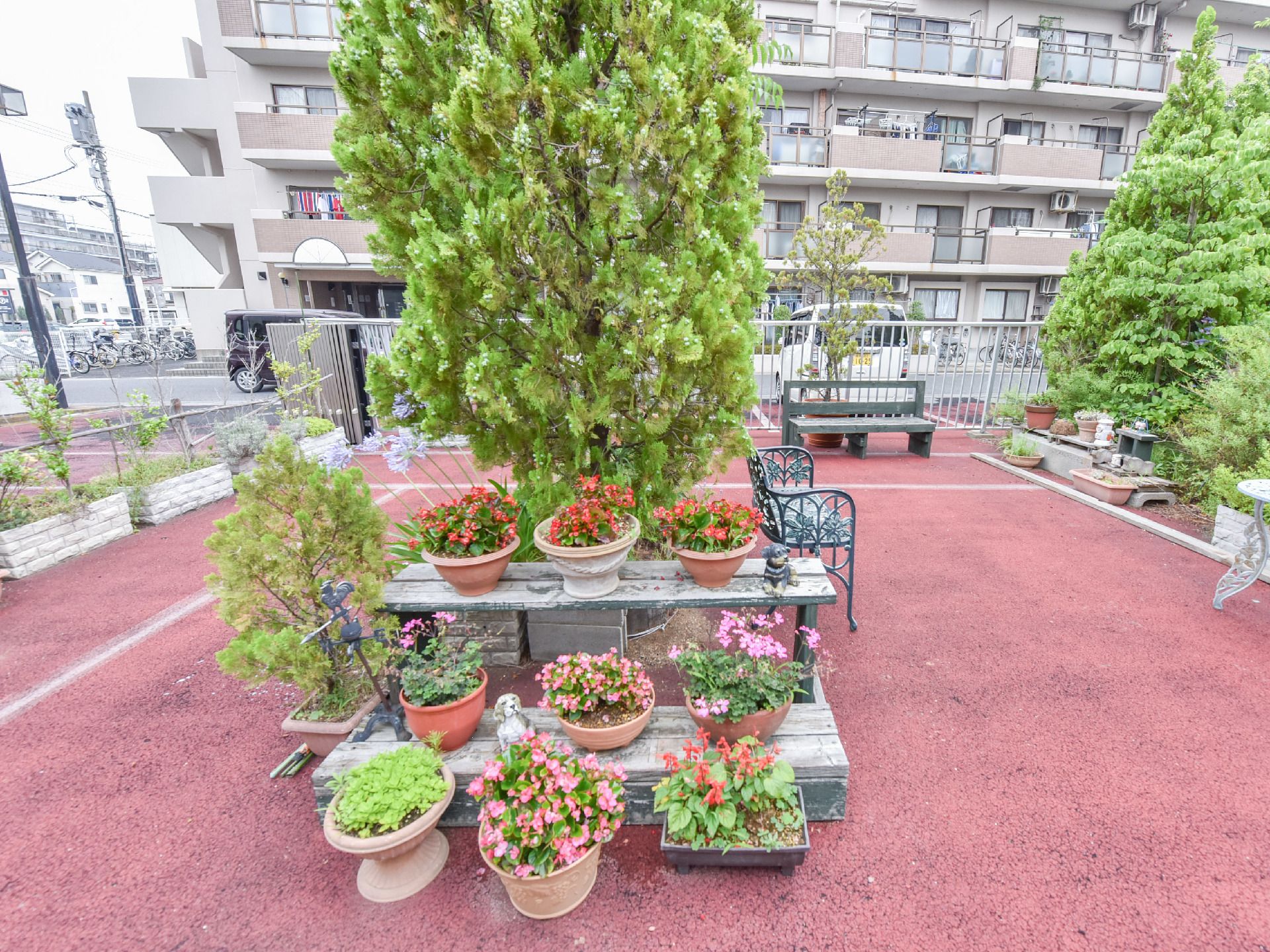 プランターにさまざまなカラフルな花が植えられている。棚は2段になっており後ろには樹木が置かれている。
