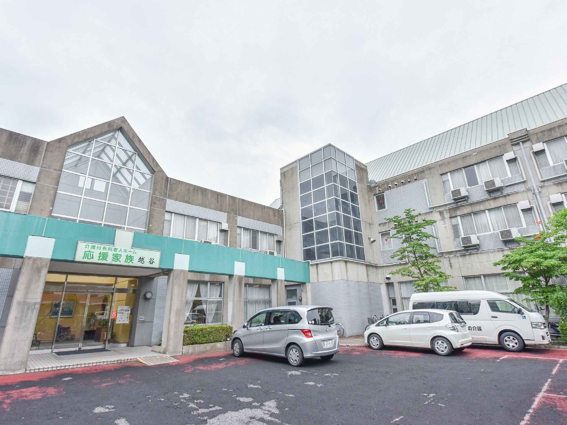 ガラス窓とコンクリートで出来た施設になっている。前面に施設名の看板が設置されており目の前は駐車場になっている。