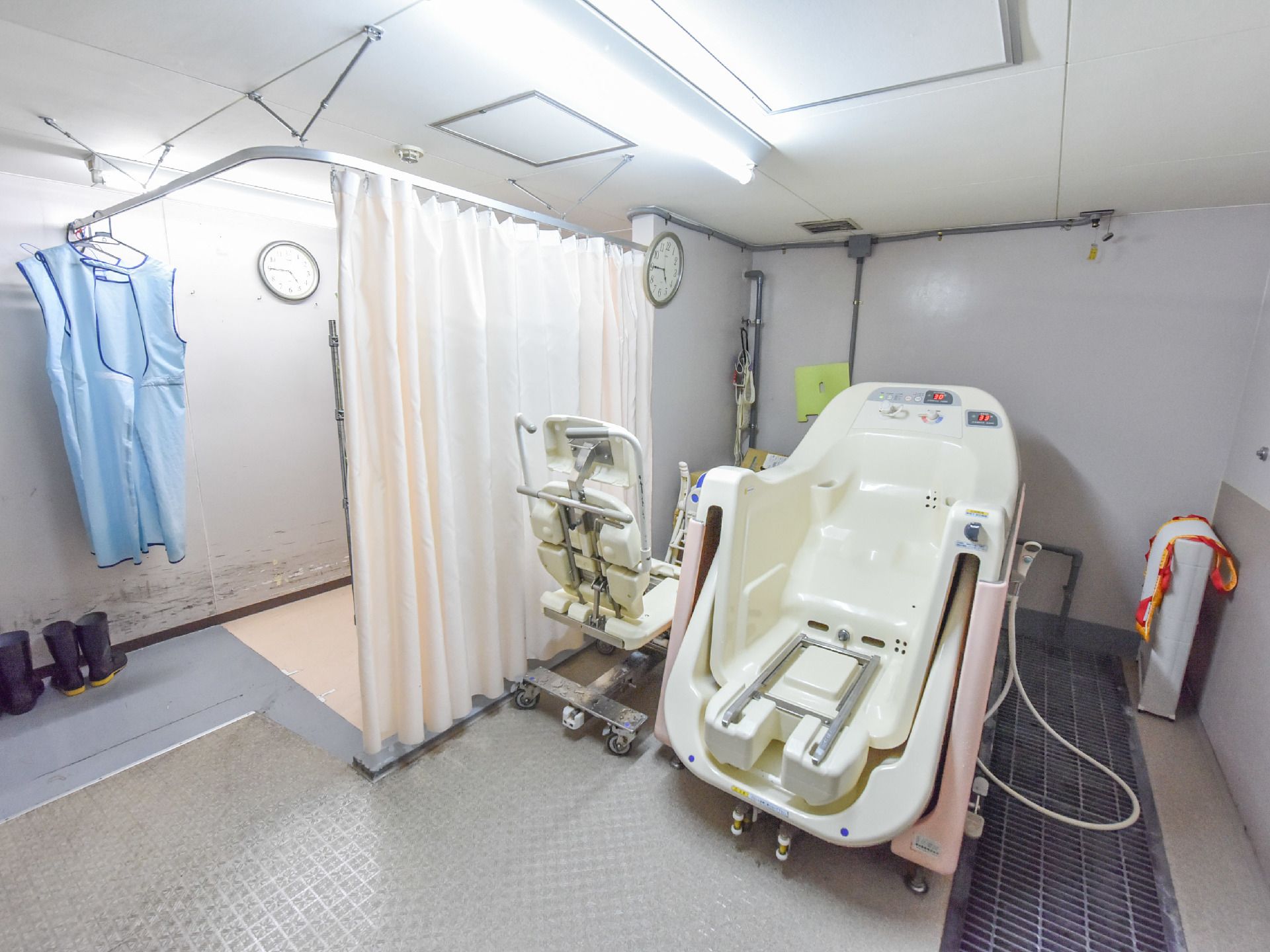 左側にはカーテンによる仕切りができるスペースがある。手前には介護専用の機材がならんでおり、床には排水溝がある。