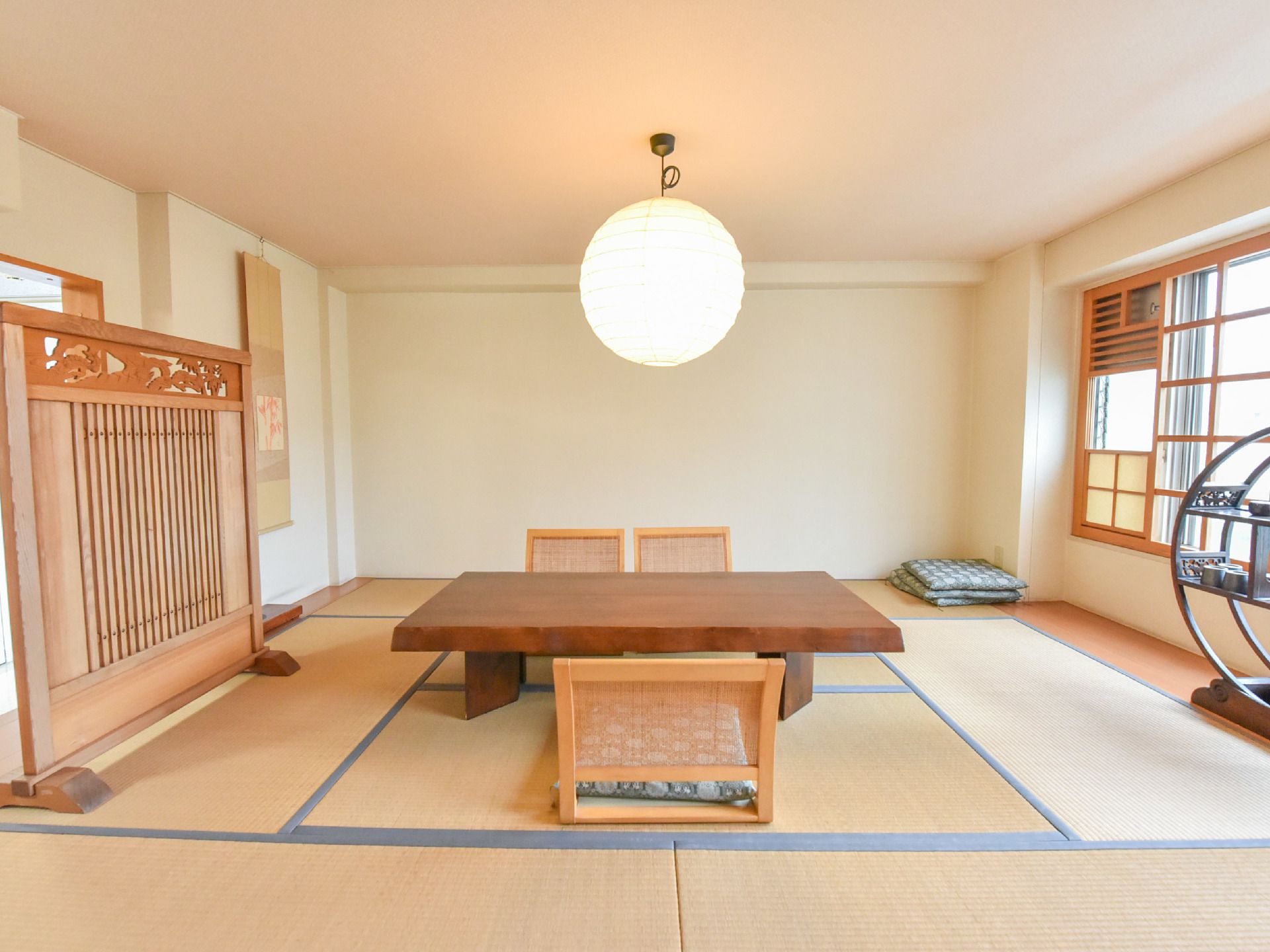 和紙を使用した照明を備え、和風の家具が置かれている、明るい畳敷きの談話室