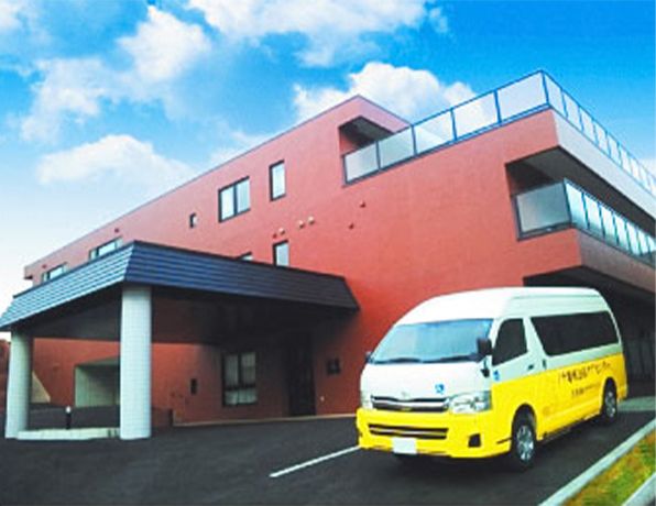 赤い壁の建物と送迎バス
