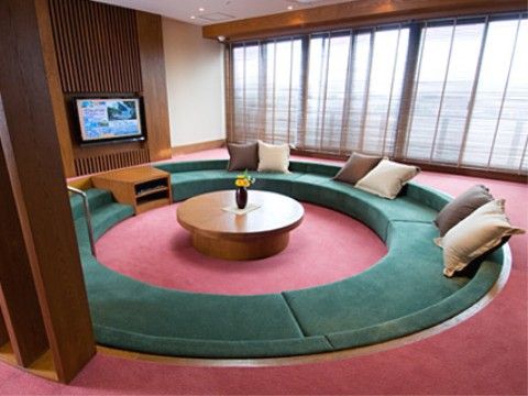 円形の大きな埋め込みソファが置かれている。床は赤のカーペット敷きとなっており、壁には大型のテレビが備え付けられている。