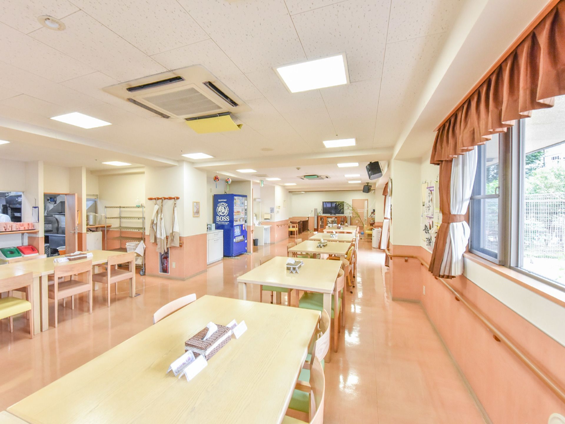空調のついた部屋には机と椅子がいくつも並んでおり、奥にはテレビや自動販売機も設置されている。窓からは光が差し込んでいる。