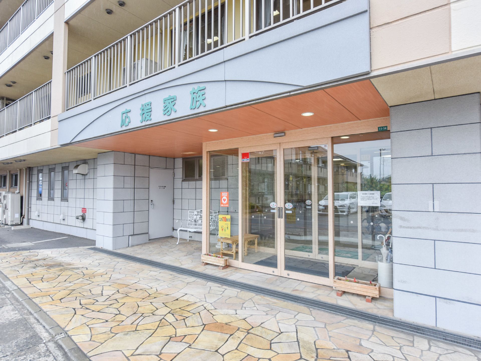 鉄筋コンクリート4階建てである。木製のプランターが玄関の両脇に置いてある。ダウンライトがついた庇がある。