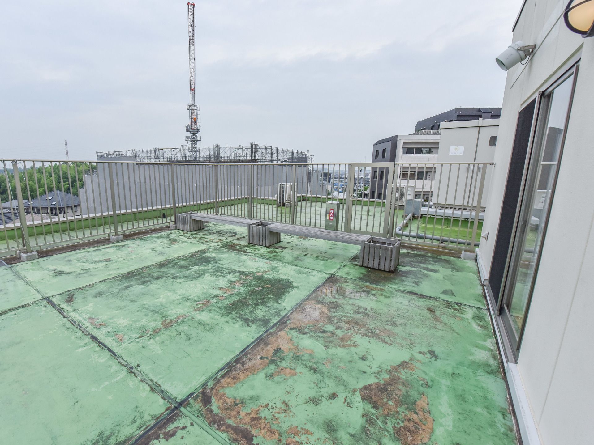 木製のベンチがある。ストライプ上のフェンスがある。消火器が設置してある。住宅街が見渡せる。屋外電源がある。