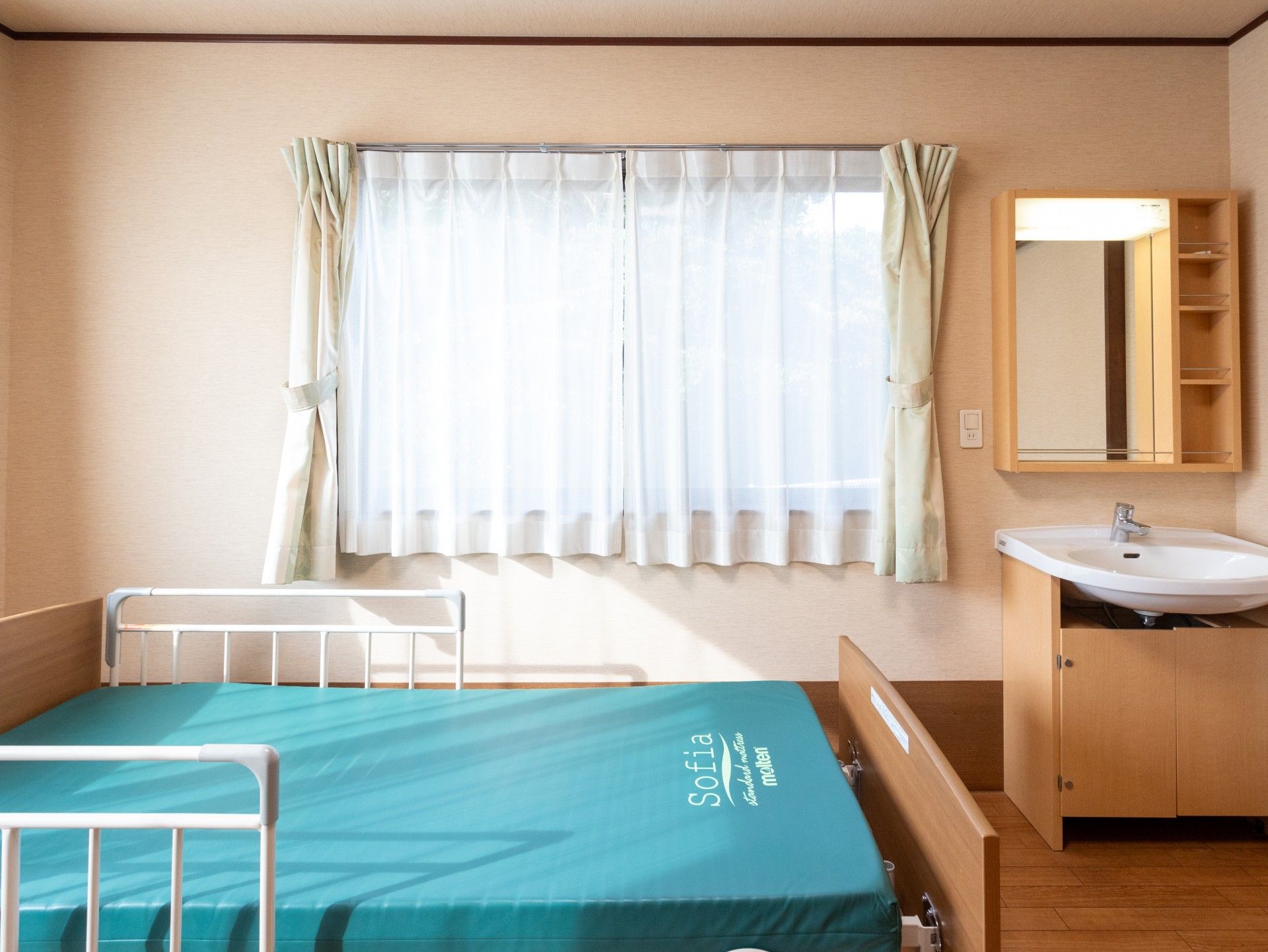 明るい個室のベッドと洗面台