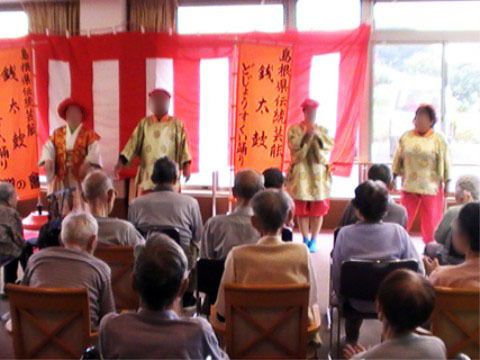 地域の伝統文化を披露するグループと、鑑賞する入居者様の様子