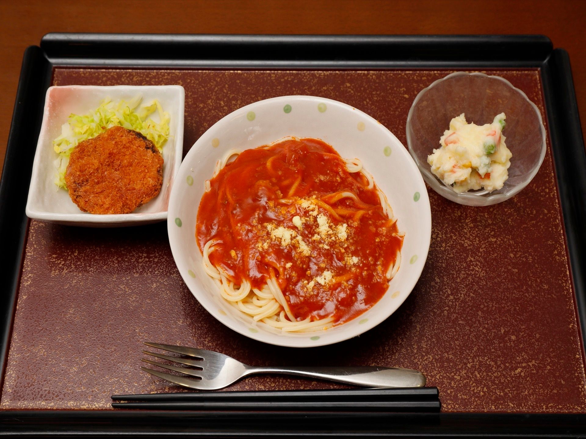 トマトソースのスパゲッティとポテトサラダ、コロッケがプレートに並べられている。入居者様のある１日の献立である。