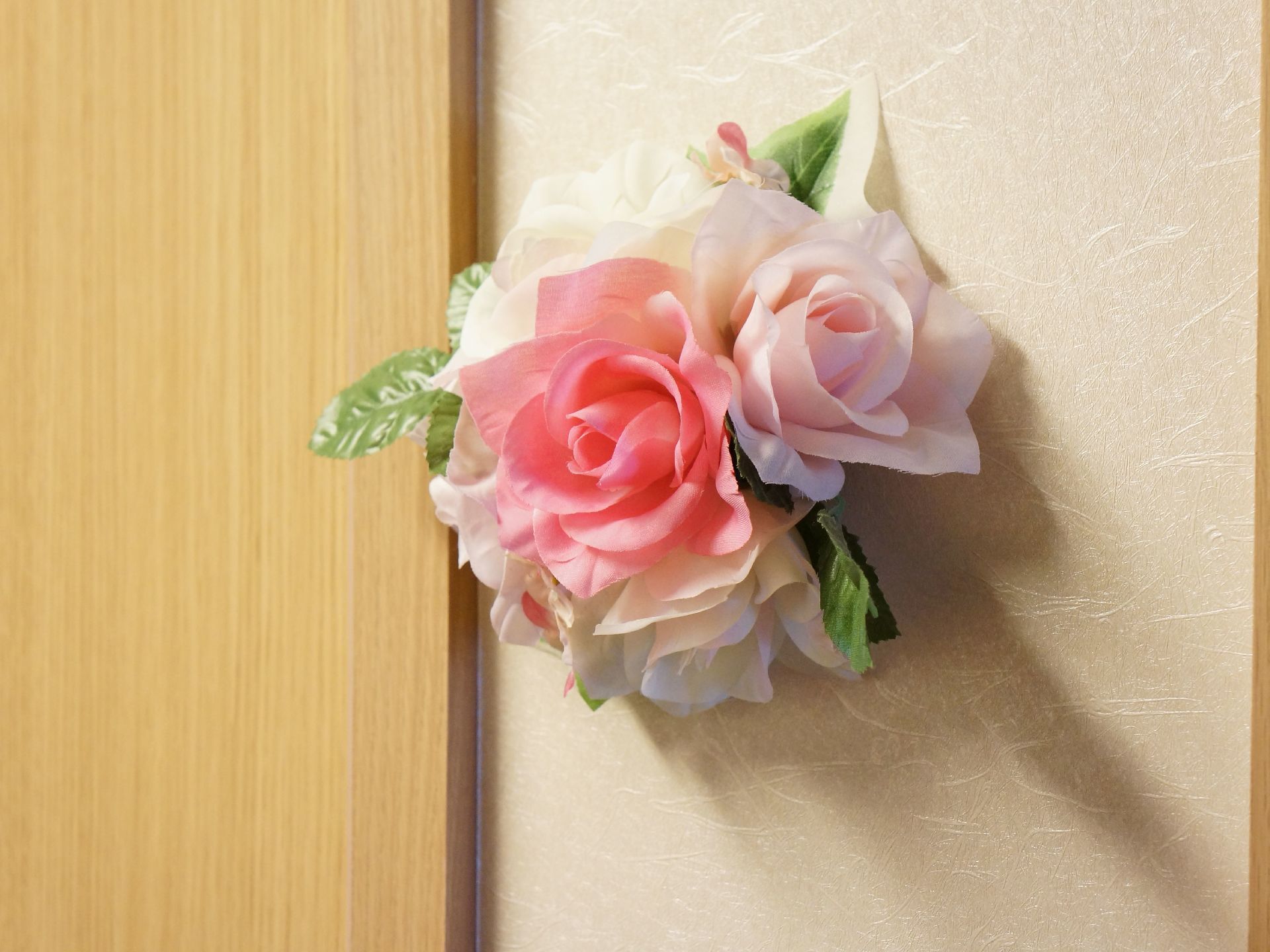 施設内の扉には木材を多く使っている。壁はアイボリー系で、部屋のドアの横にはバラの花の造花を飾っている。