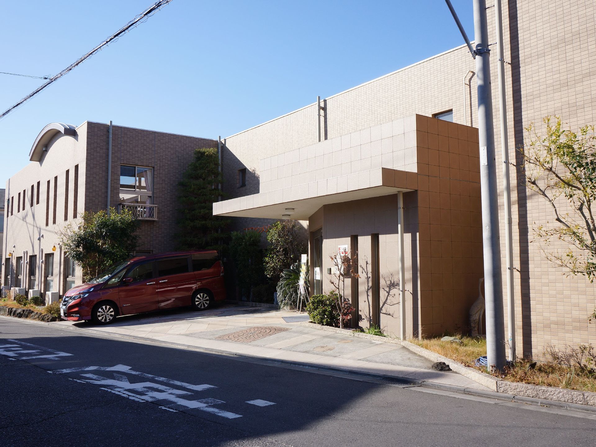 施設の建物は二階建てで、外壁は明るいブラウン系のタイル張りである。前面には樹木を植え、駐車場を設けている。