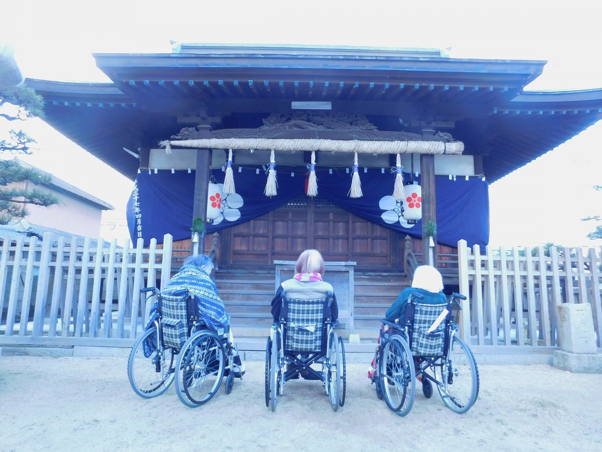 車椅子の方々と神社の門
